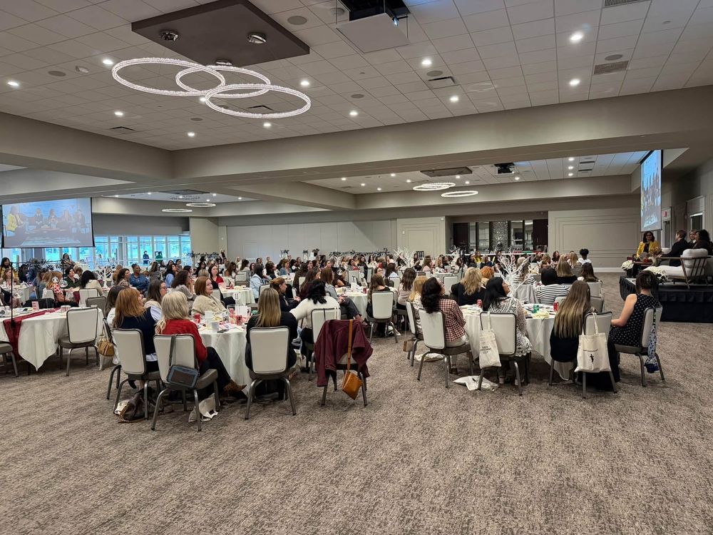 A ballroom full of women seated at round tables during the Women Rising Summit