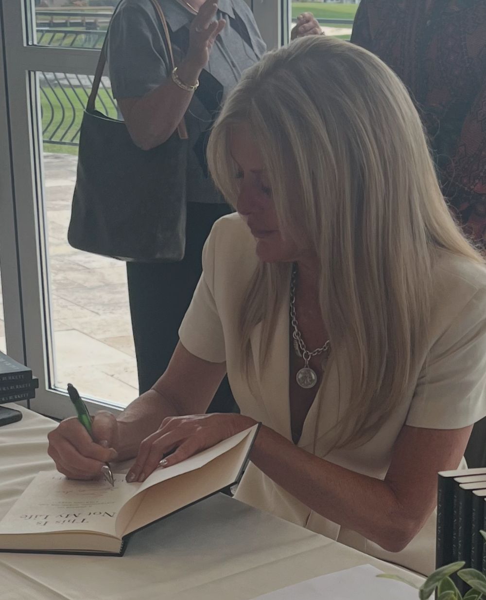 Author Laura Burkett signing a copy of This Is Not My Life at her book table